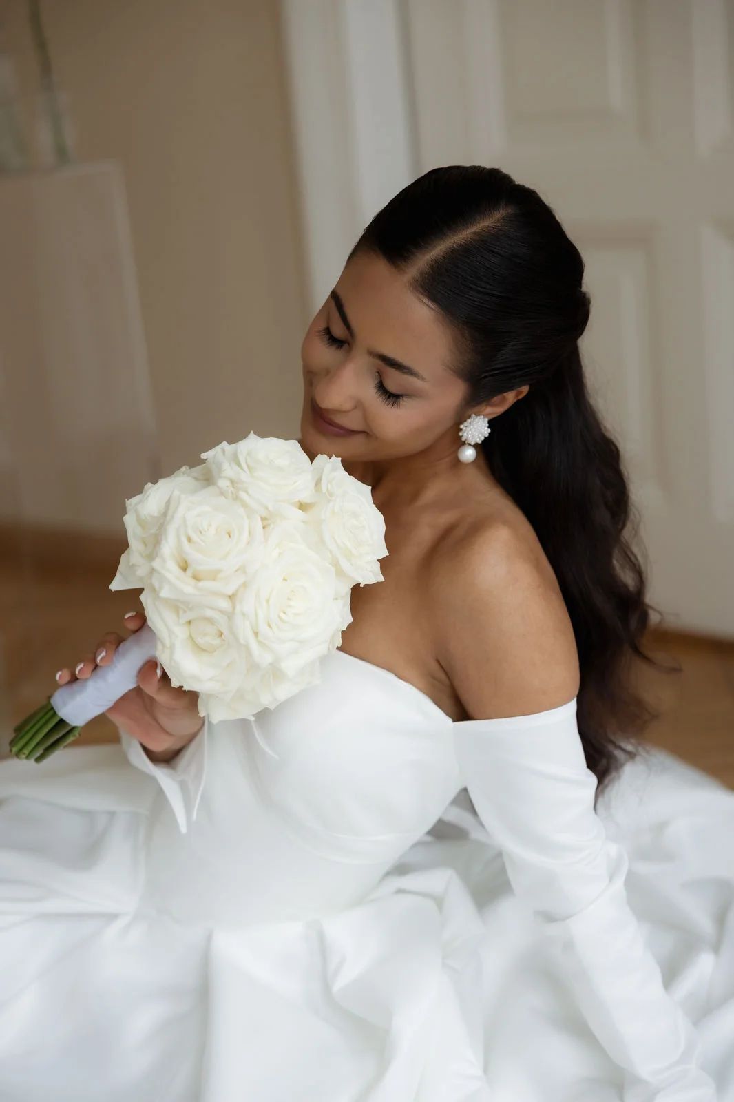 Braut mit weißem Rosenstrauß in einem modernen Brautkleid mit Carmen-Ausschnitt
