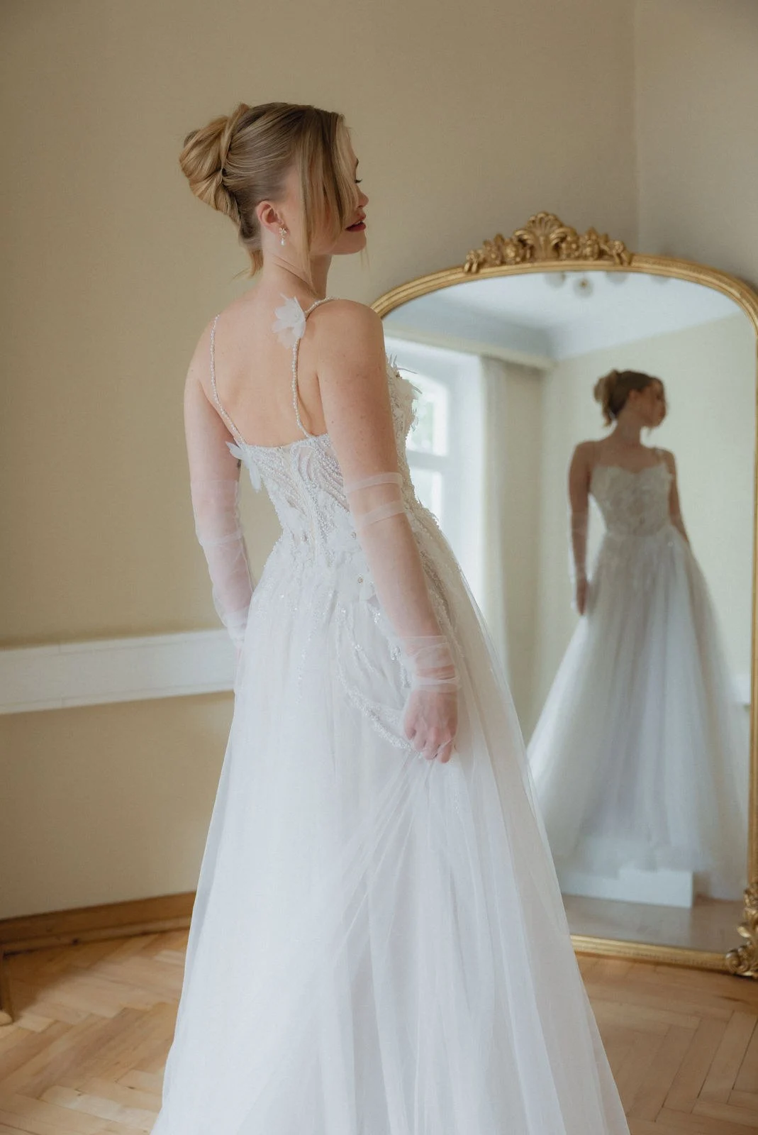 Braut vor dem goldgerahmten Spiegel im Love Edit Bridalstore Bamberg bei der Brautkleid-Anprobe