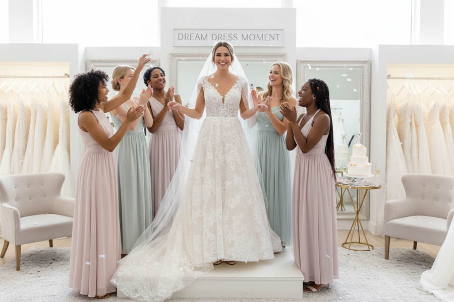 Braut steht im Kreis mit Freundinnen Anprobe